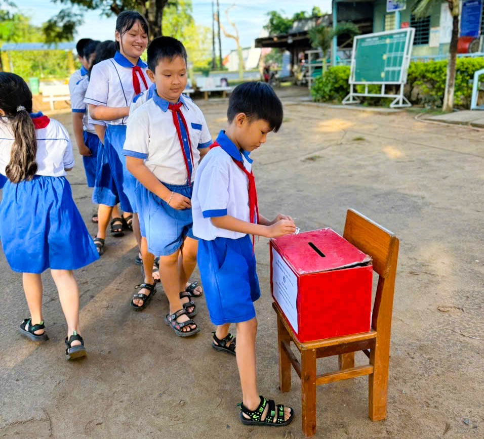 Description: A group of children in uniform putting a box in a boxAI-generated content may be incorrect.