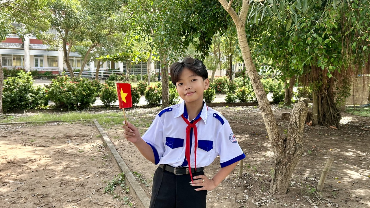 Description: A child in uniform holding a flag
AI-generated content may be incorrect.