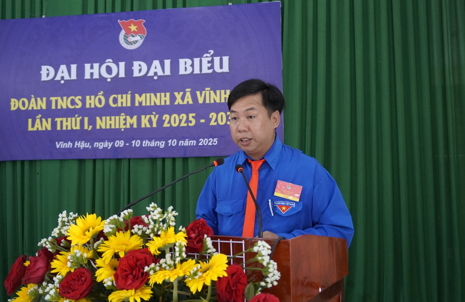 Description: A person standing at a podium with flowersAI-generated content may be incorrect.