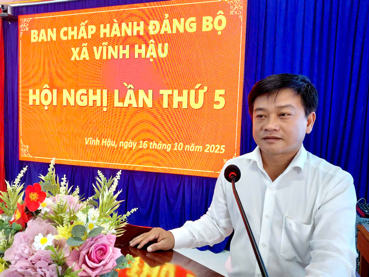 Description: A person sitting at a podium with a microphoneAI-generated content may be incorrect.